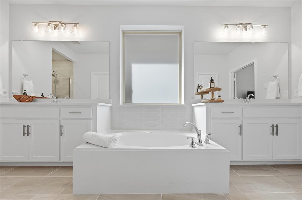 9317 Sunset Lane Oak Point, TX 75068 - Photo 16 of 40 a bathroom with a bathtub a double vanity sink and mirror