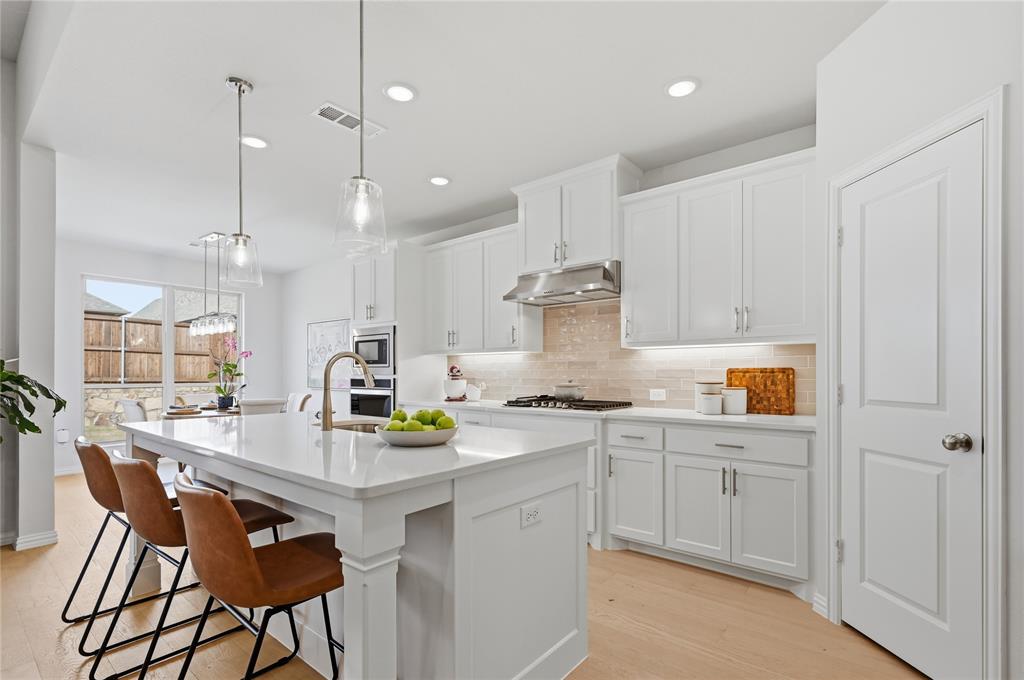 9317 Sunset Lane Oak Point, TX 75068 - Photo 3 of 40 a kitchen with a sink a stove a refrigerator and white cabinets
