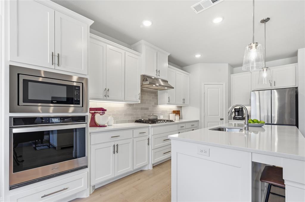 9317 Sunset Lane Oak Point, TX 75068 - Photo 9 of 40 a kitchen with kitchen island a stove a sink and a microwave