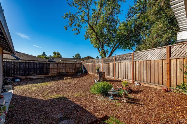 a view of a backyard with wooden fence and a bench