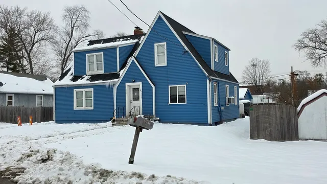 a front view of a house with a yard covered in snow