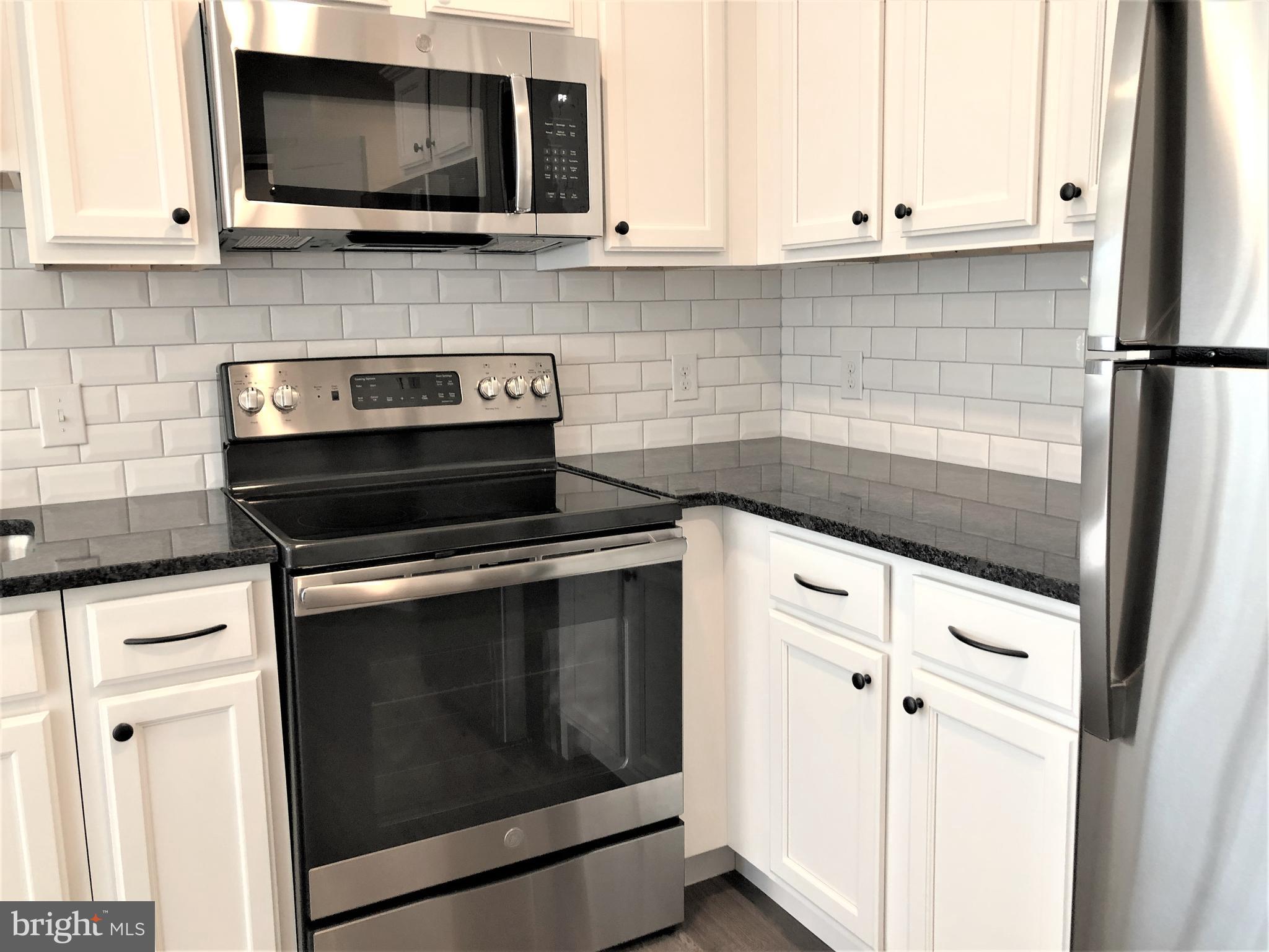 a kitchen with stainless steel appliances white cabinets and a stove top oven