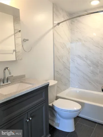 a bathroom with a granite countertop sink a toilet and shower