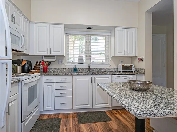 a kitchen with granite countertop white cabinets and white appliances