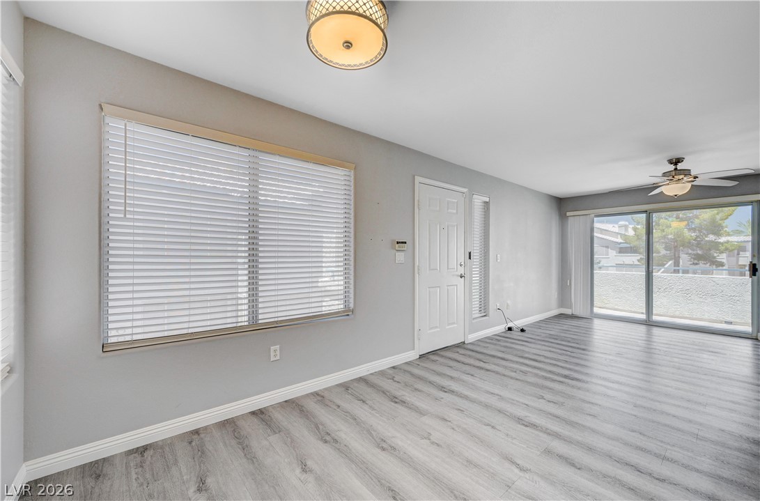 3425 East Russell Road, Unit 223 Las Vegas, NV 89120 - Photo 16 of 47 Natural light pours into this living space, featuring durable laminate flooring and a functional ceiling fan.