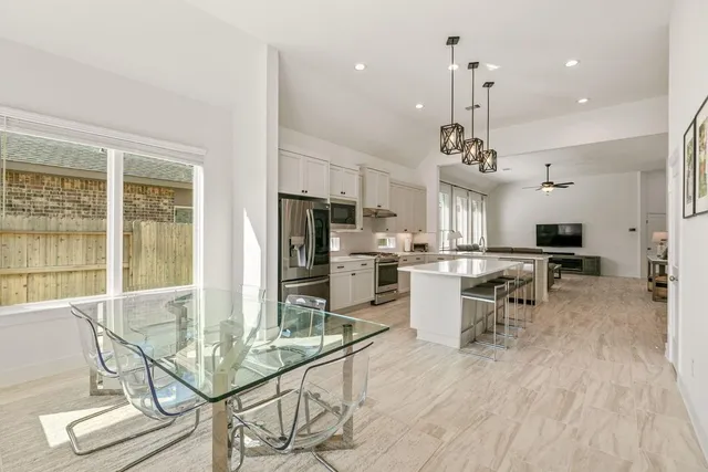 a kitchen with stainless steel appliances kitchen island granite countertop a table chairs and a view of living room