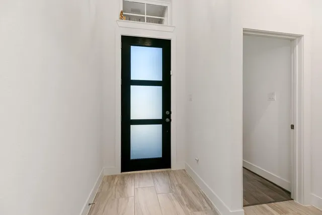a view of a hallway with wooden floor and a bathroom
