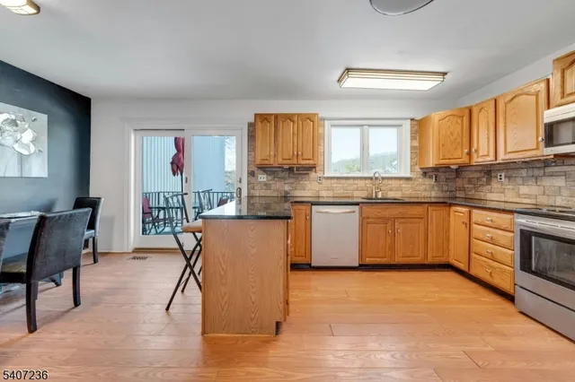 a kitchen with stainless steel appliances granite countertop a stove top oven a sink dishwasher and white cabinets with wooden floor