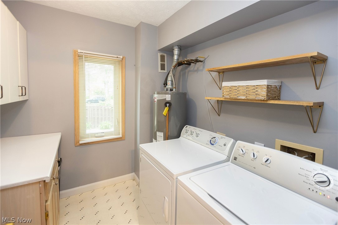 19510 Lorain Road, Unit 101 Cleveland, OH 44126 - Photo 20 of 24 Laundry room with washing machine and dryer, light vinyl flooring, water heater, hookup for a washing machine, and cabinets