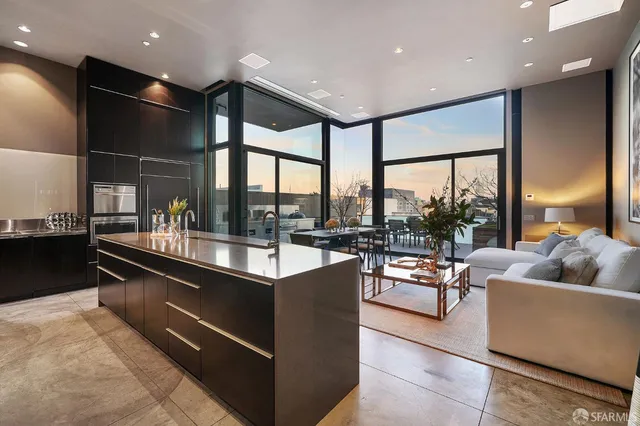 a living room with stainless steel appliances kitchen island granite countertop a couch and a large window