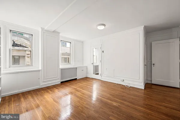 a view of an empty room with wooden floor and windows