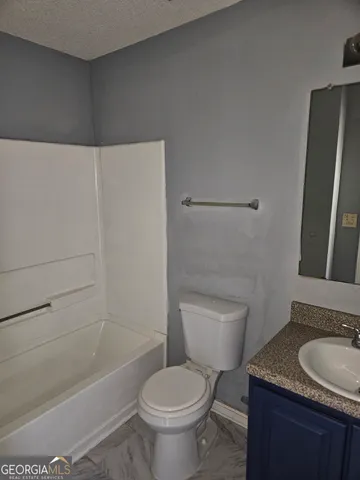a bathroom with a granite countertop toilet sink and mirror