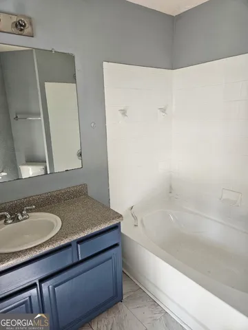 a bathroom with a granite countertop sink and a bathtub