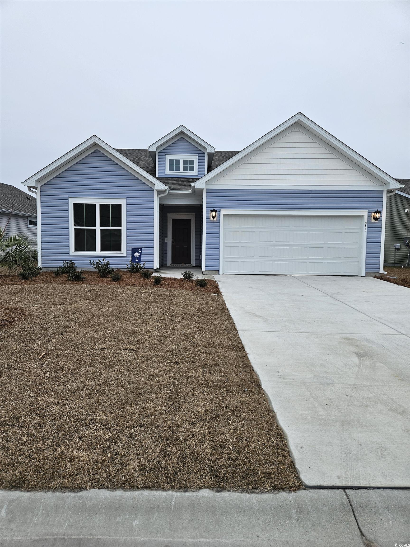 Traditional home featuring driveway, a garage, and roof with shingles