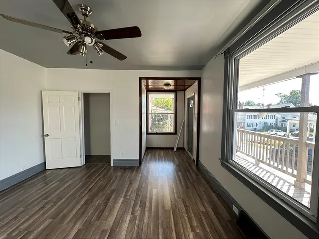 a view of an empty room with wooden floor and a window