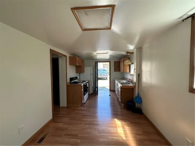 a view of a hallway with the kitchen and wooden floor
