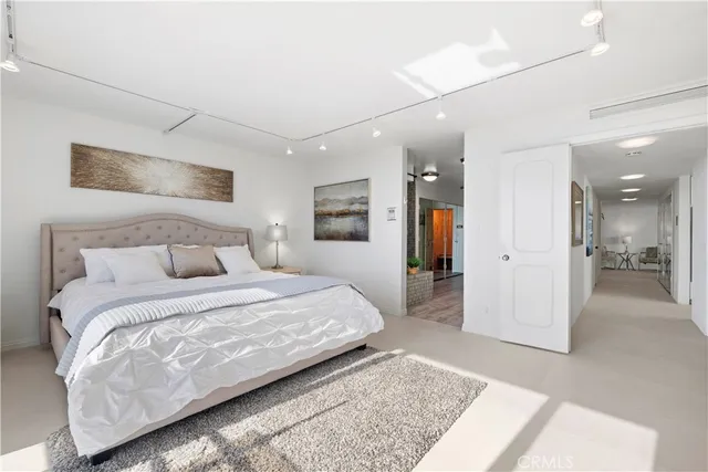 a bedroom with a large bed a rug and painting on the wall