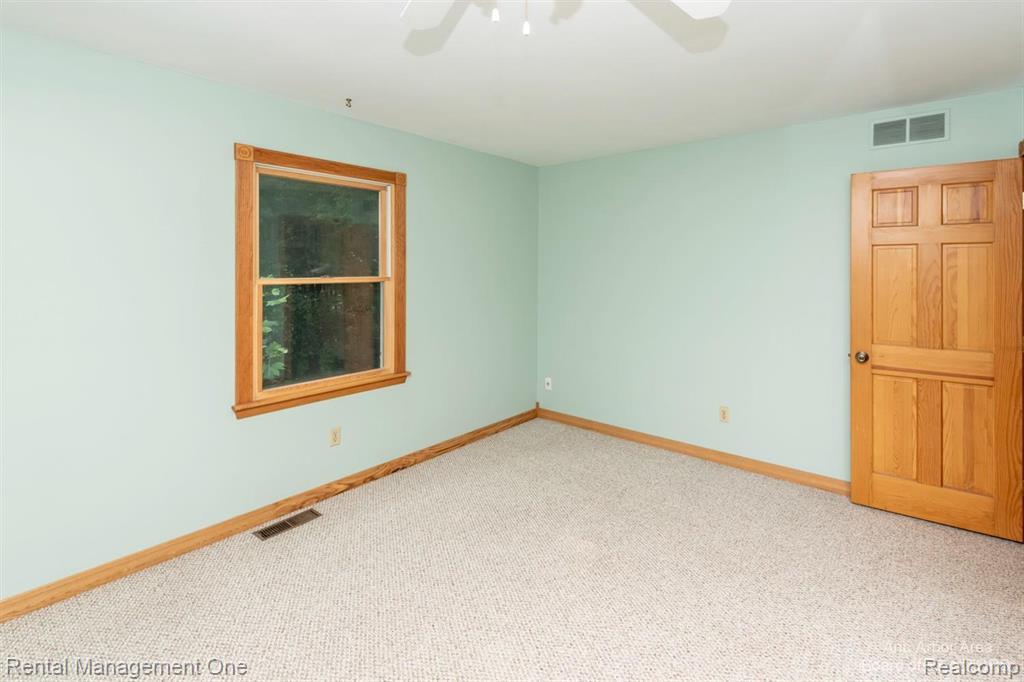 7870 Chamberlin Road Dexter, MI 48130 - Photo 28 of 52 Carpeted room with a ceiling fan, a window with wood trim, wood-paneled door, and wood baseboards