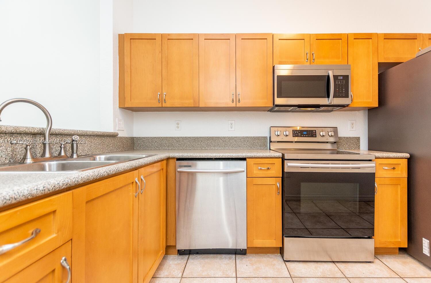 4979 Southwest 140th Terrace, Unit 8 Miramar, FL 33027 - Photo 20 of 43 a kitchen with stainless steel appliances granite countertop a stove a sink and a microwave