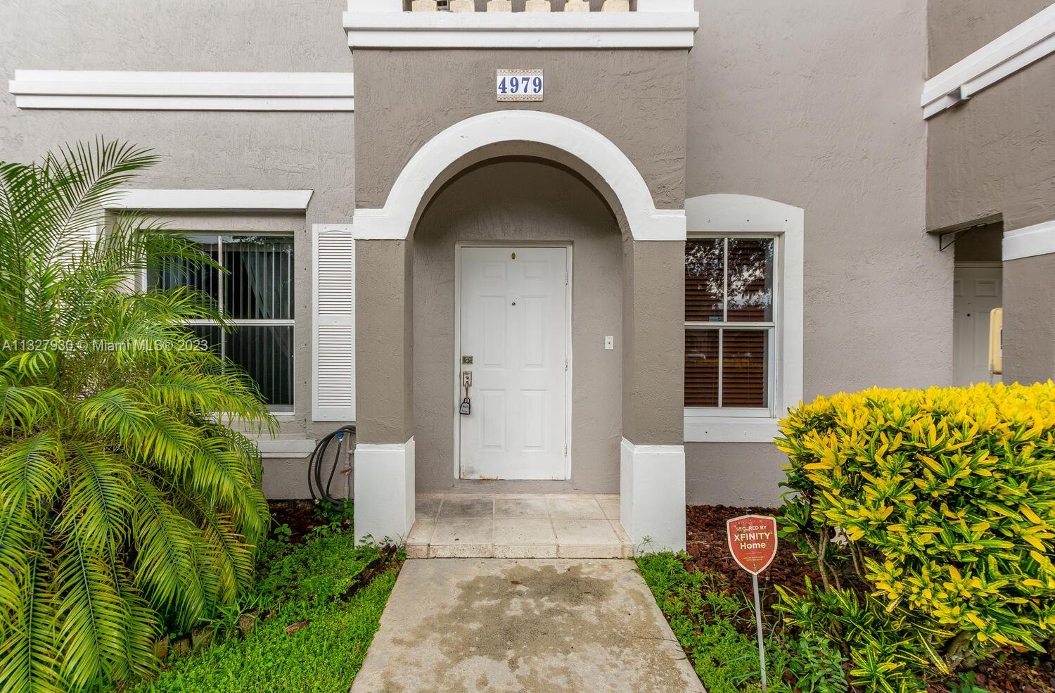 4979 Southwest 140th Terrace, Unit 8 Miramar, FL 33027 - Photo 4 of 43 a front view of a house with garden