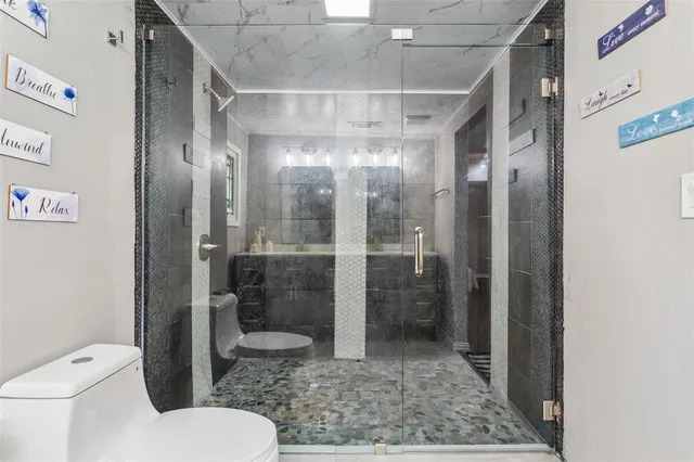 a bathroom with a glass door shower and toilet