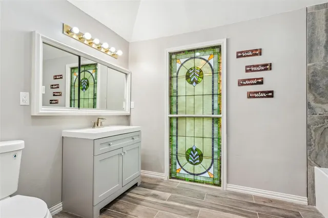 a bathroom with a sink a toilet and next to a window