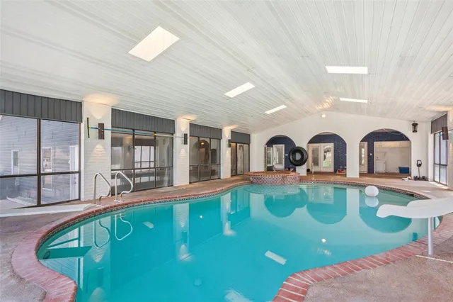 an empty room with chandelier fan and windows