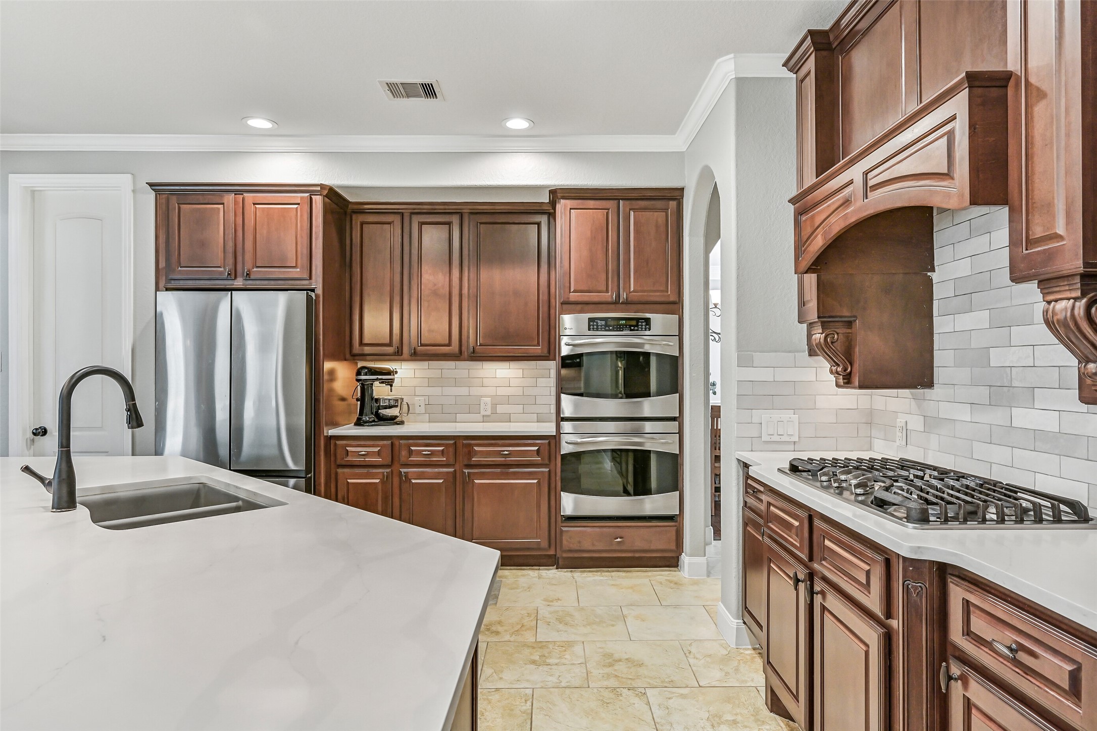 1008 Point Isabel Lane Friendswood, TX 77546 - Photo 15 of 50 A full appliance wall includes double convection ovens, a built-in microwave, a 5 burner gas cooktop, and extensive cabinetry for storage. Under cabinet lighting and a subway tile backsplash enhance both function and visual appeal.