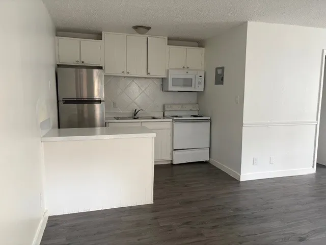 a kitchen with stainless steel appliances granite countertop a refrigerator a sink a stove a microwave and white cabinets