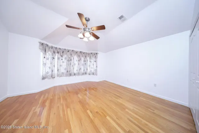 a view of empty room with wooden floor and ceiling fan