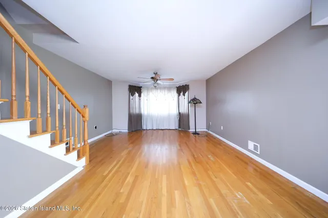 a view of an empty room with wooden floor and staircase