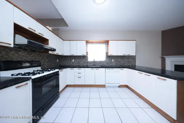 a kitchen with granite countertop a stove a sink and a microwave