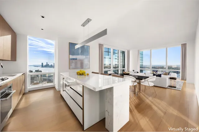 a view of a kitchen with kitchen island a sink a counter top space a stove and cabinets