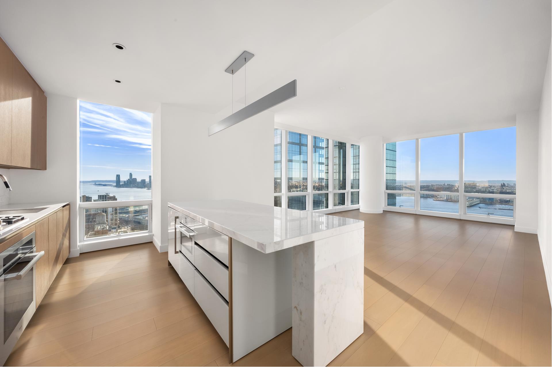 15 Hudson Yards, Unit 38C Manhattan, NY 10001 - Photo 7 of 31 a view of a kitchen with kitchen island a sink a counter top space a stove and cabinets