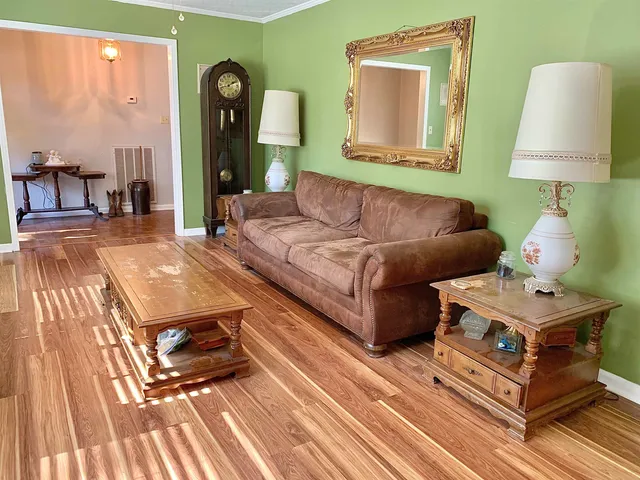 a living room with couches dresser and a table with wooden floor