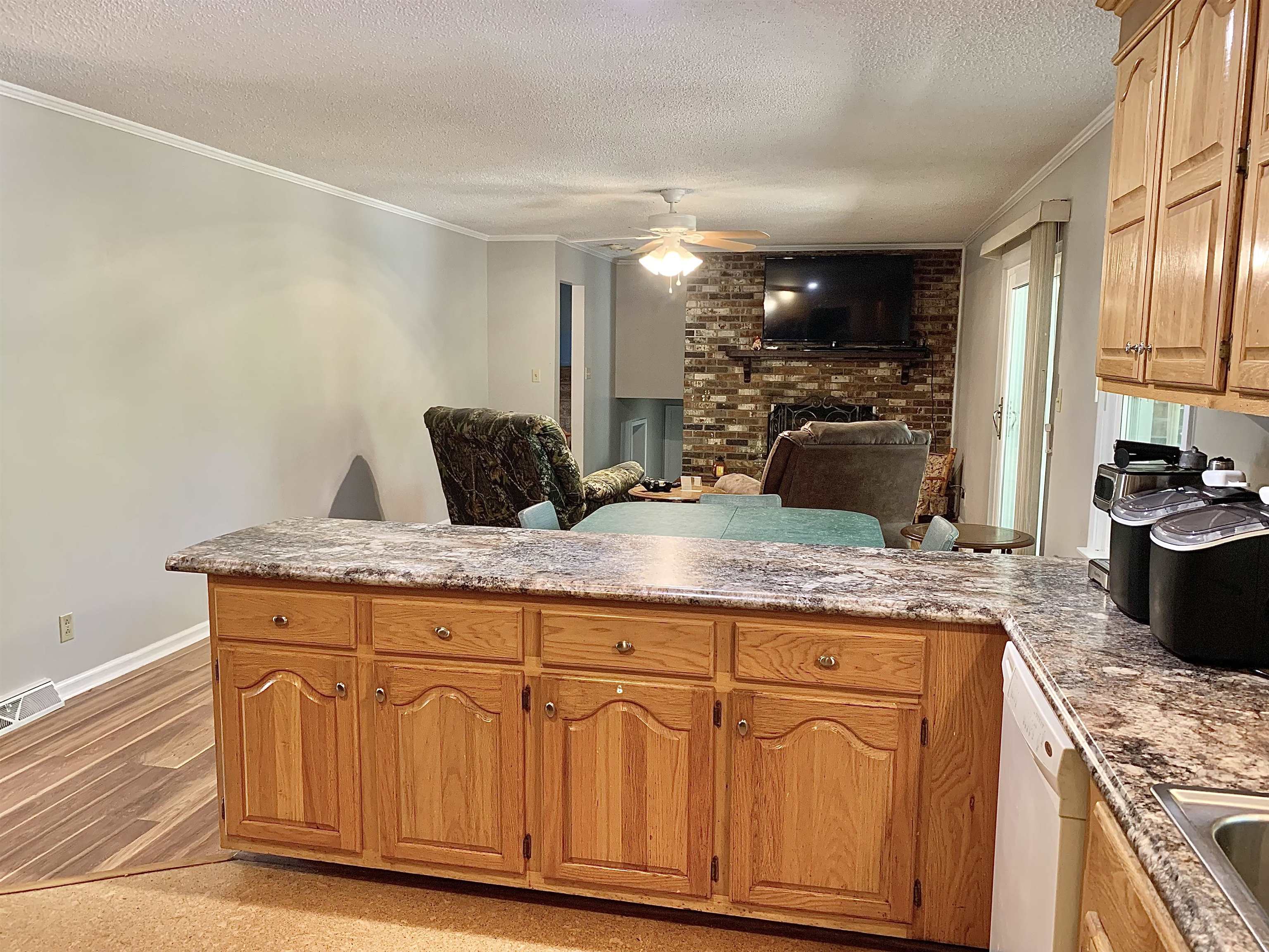 1038 Lake Street Bolivar, TN 38008 - Photo 6 of 31 Kitchen featuring light wood-type flooring, white dishwasher, kitchen peninsula, a brick fireplace, and ornamental molding