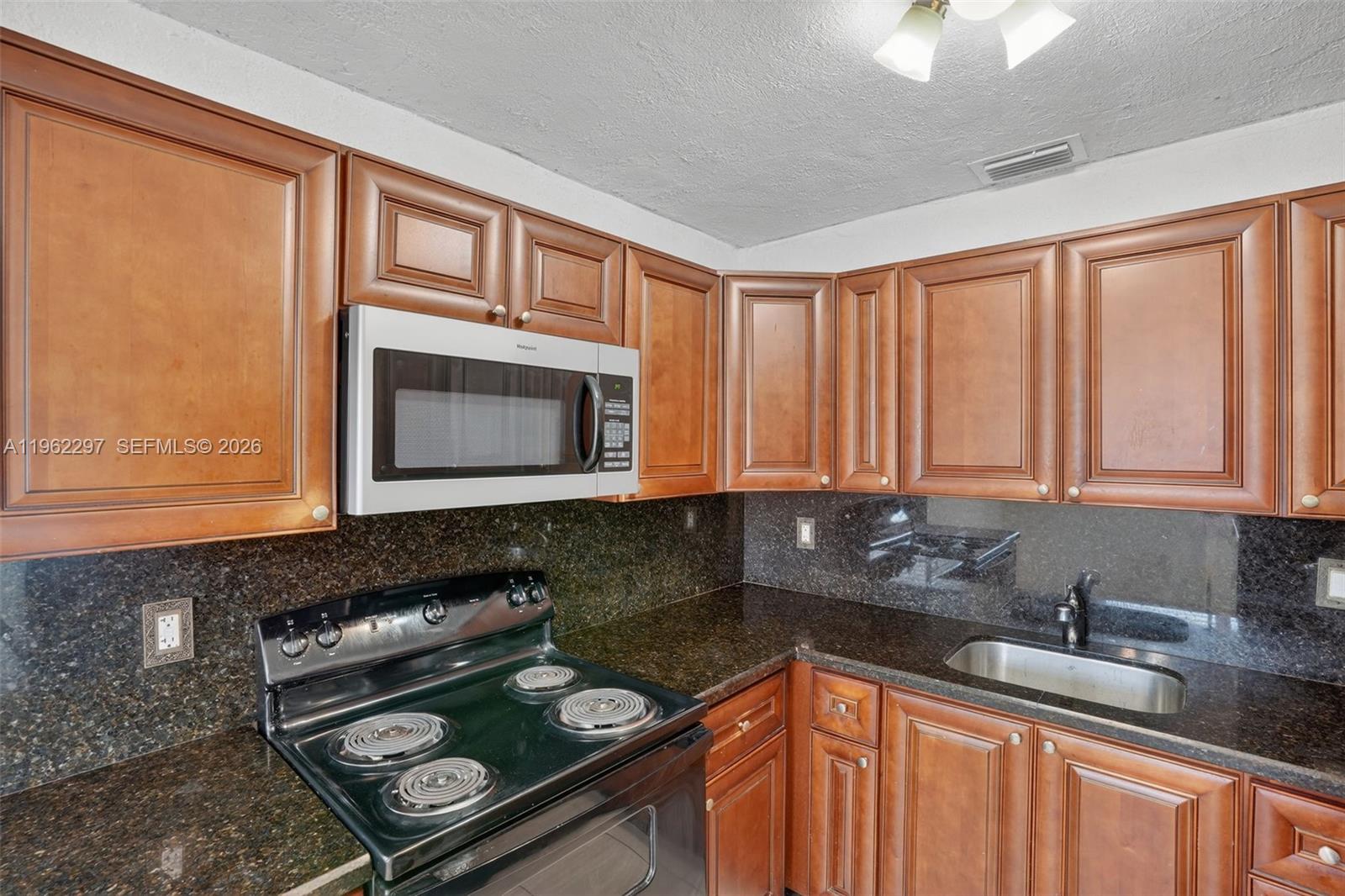 10325 Southwest 149th Terrace Miami, FL 33176 - Photo 31 of 34 a kitchen with granite countertop a stove sink and cabinets