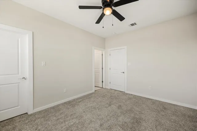 an empty room with windows and ceiling fan
