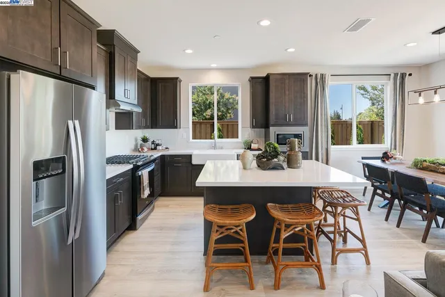 a kitchen with stainless steel appliances a dining table chairs refrigerator and microwave