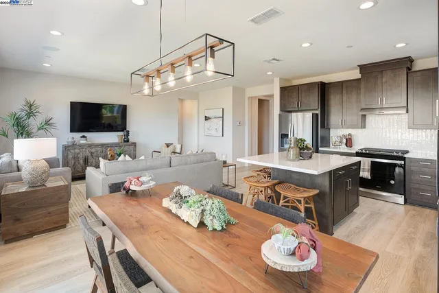 a living room with stainless steel appliances kitchen island granite countertop furniture and a flat screen tv