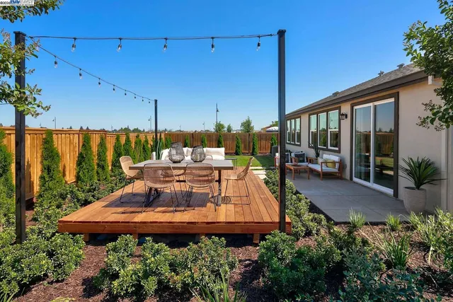 a view of a patio with table and chairs potted plants with floor to ceiling window and potted plants