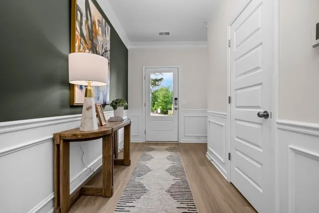 a view of a hallway to a bedroom with wooden floor and windows