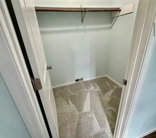 a view of walk in closet with wooden floor and stairs