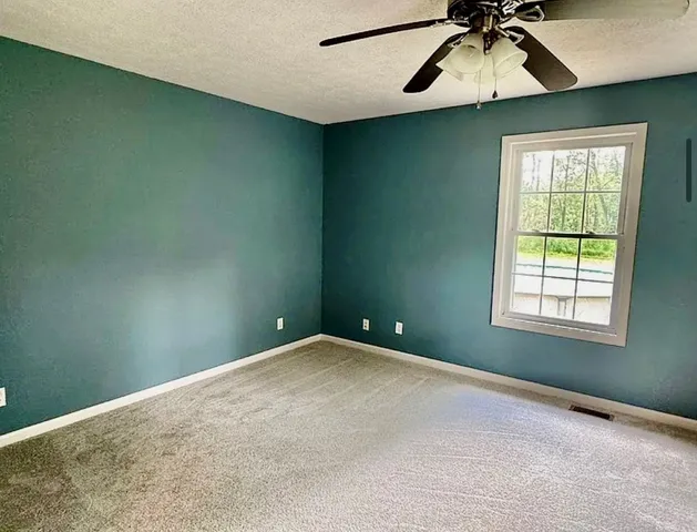 an empty room with a window and a ceiling fan