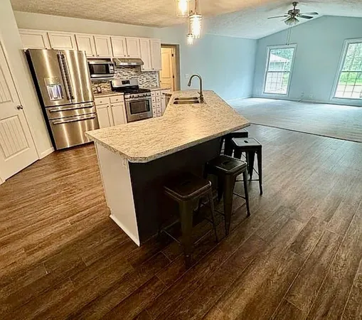 a kitchen with granite countertop a refrigerator and steel stove top oven
