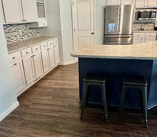 a kitchen with kitchen island granite countertop a dining table chairs and a wooden floor