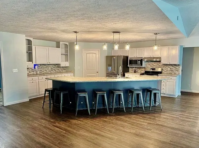 a large kitchen with kitchen island a sink stainless steel appliances and cabinets