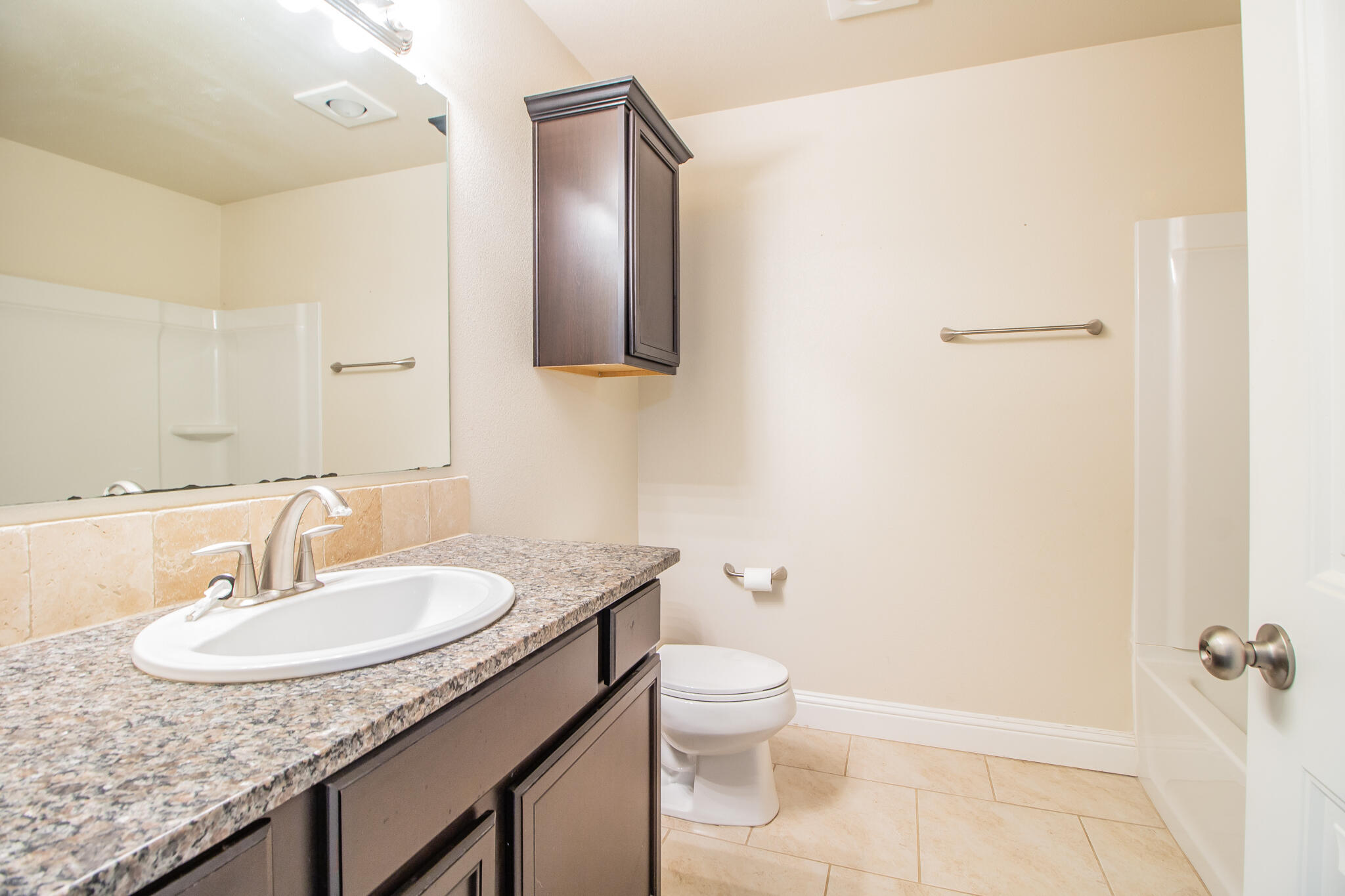 7409 101st Street Lubbock, TX 79424 - Photo 12 of 22 a bathroom with a granite countertop sink toilet and shower