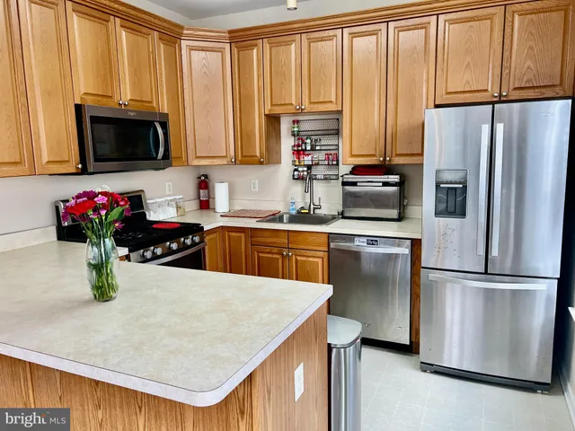 a kitchen with stainless steel appliances a stove a sink a microwave a refrigerator and cabinets