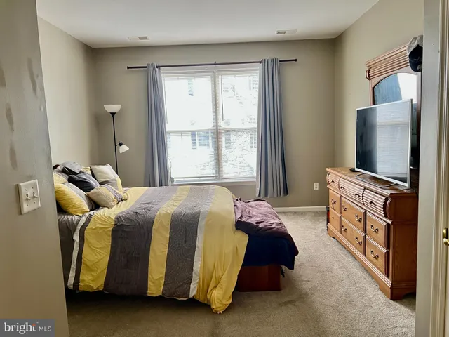 a bedroom with a bed and a flat tv screen next to a window